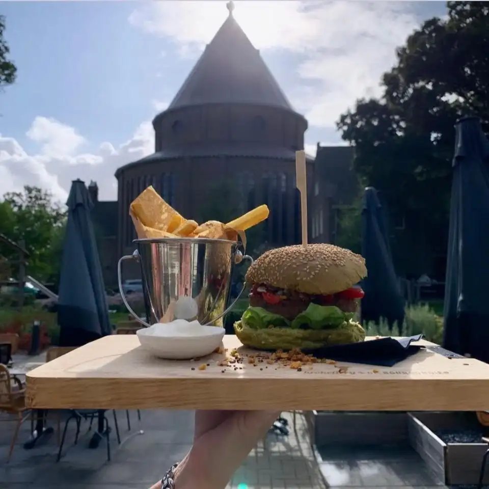 Plank met burger en friet met Cultuurkoepel op de achtergrond